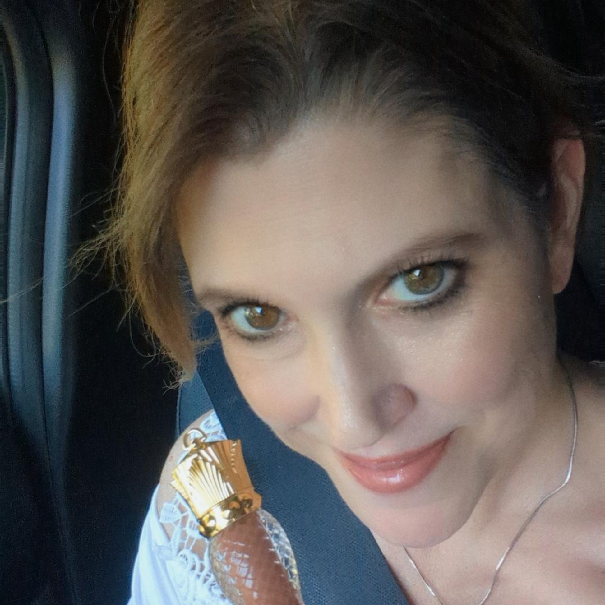 Woman holding a gold lipstick in a car